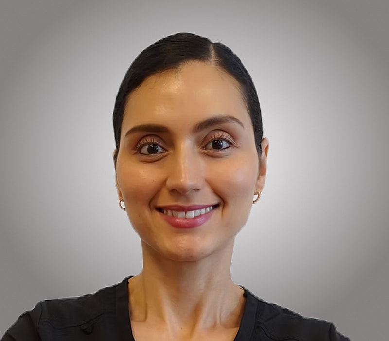 Smiling woman in professional attire, neutral background.