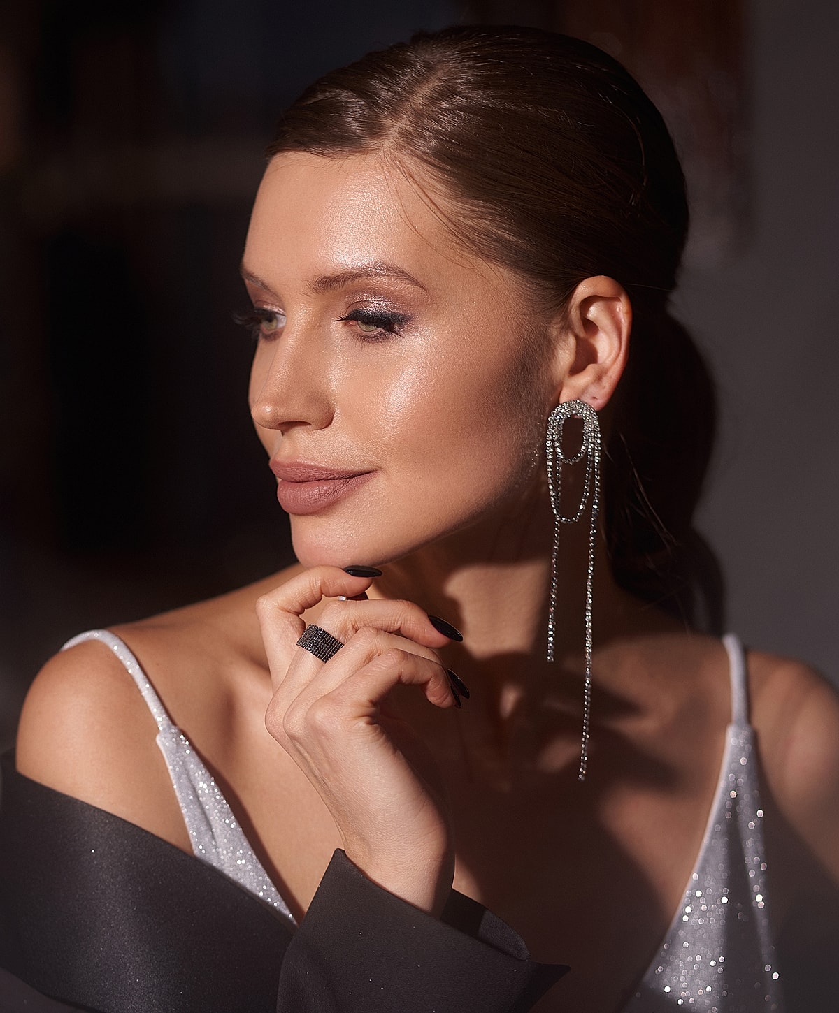 Elegant woman with jewelry and thoughtful expression.