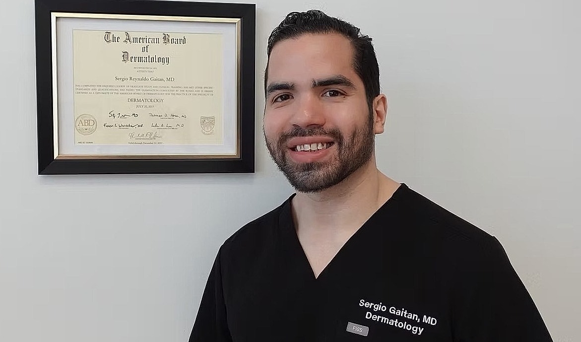 Dermatologist with certification on display.