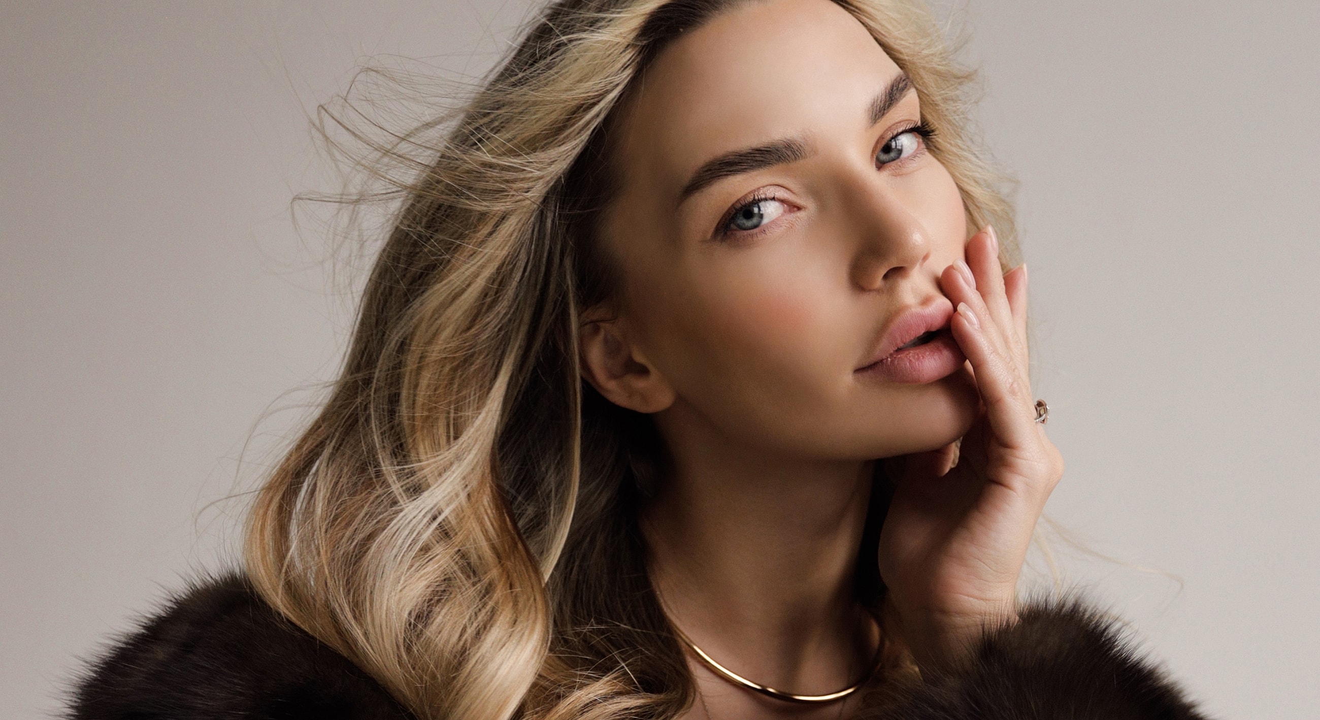 Blonde woman with elegant hairstyle and jewelry.